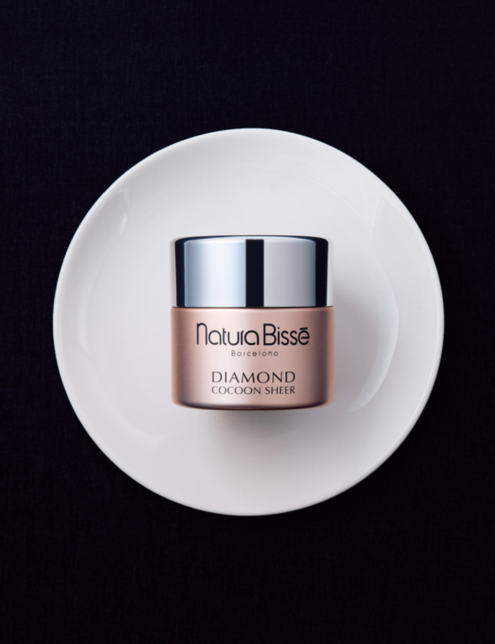 Woman holding with both hands Natura Bissé's Diamond Cocoon Sheer Cream. This cream is both a moisturizer and offers a touch of colour.