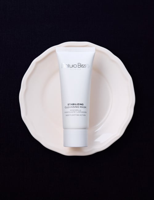 Woman holding Natura Bissé's Stabilizing Cleansing Mask. Skincare product featured in bestsellers.