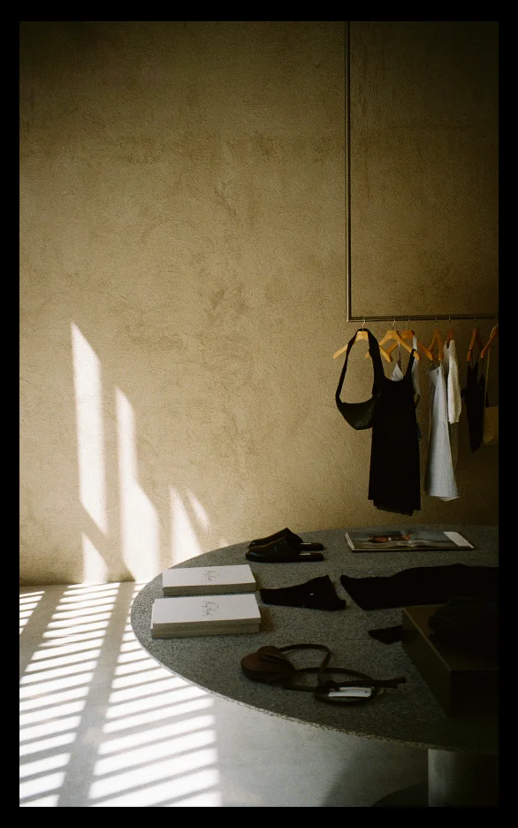 Table featuring a selection of accesories sold at MIG and a rack with clothes